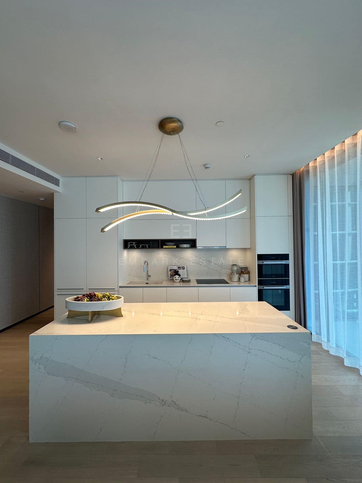 The kitchen of a three-bedroom residence at EI8HTEEN SEVEN, One Bangkok, with a marble waterfall island and integrated appliances