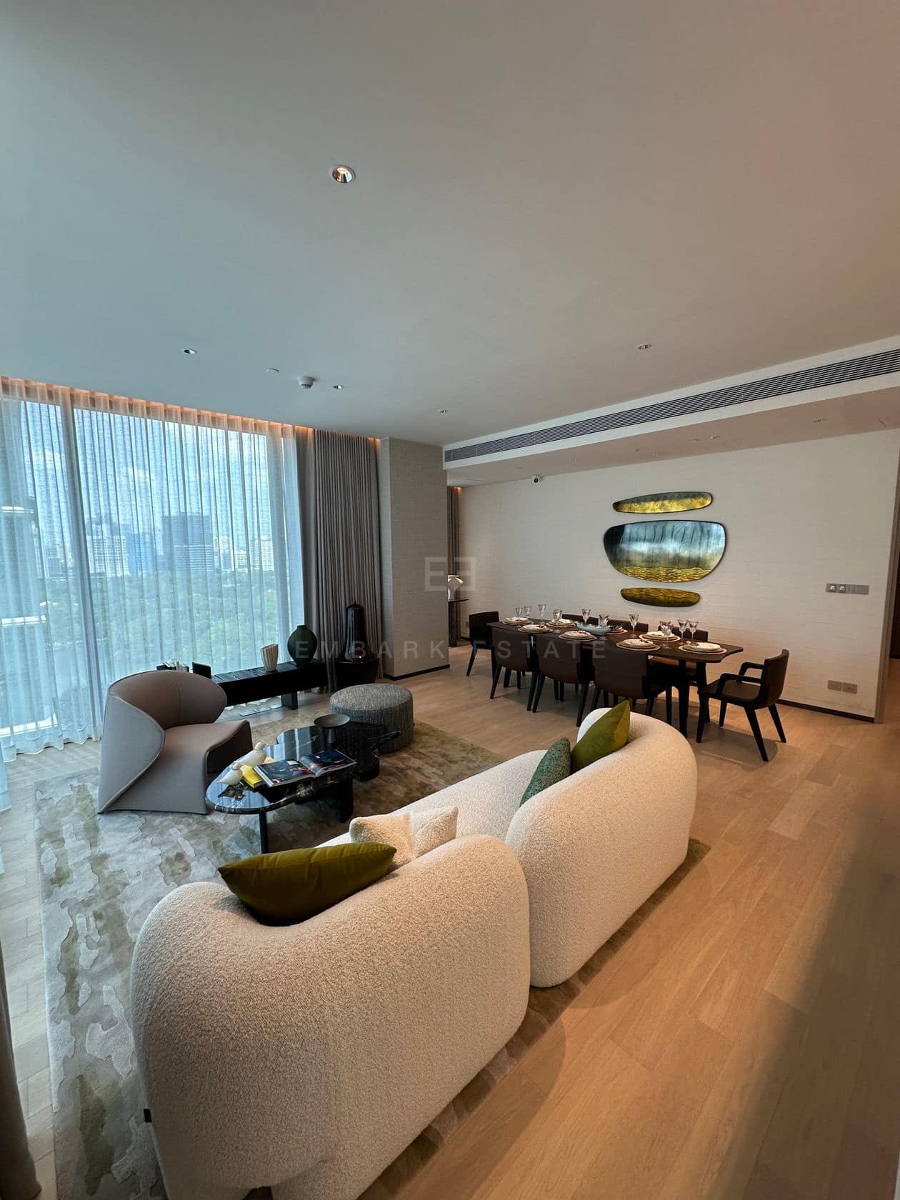 The living and dining area of a three-bedroom residence at EI8HTEEN SEVEN, One Bangkok, with floor-to-ceiling windows