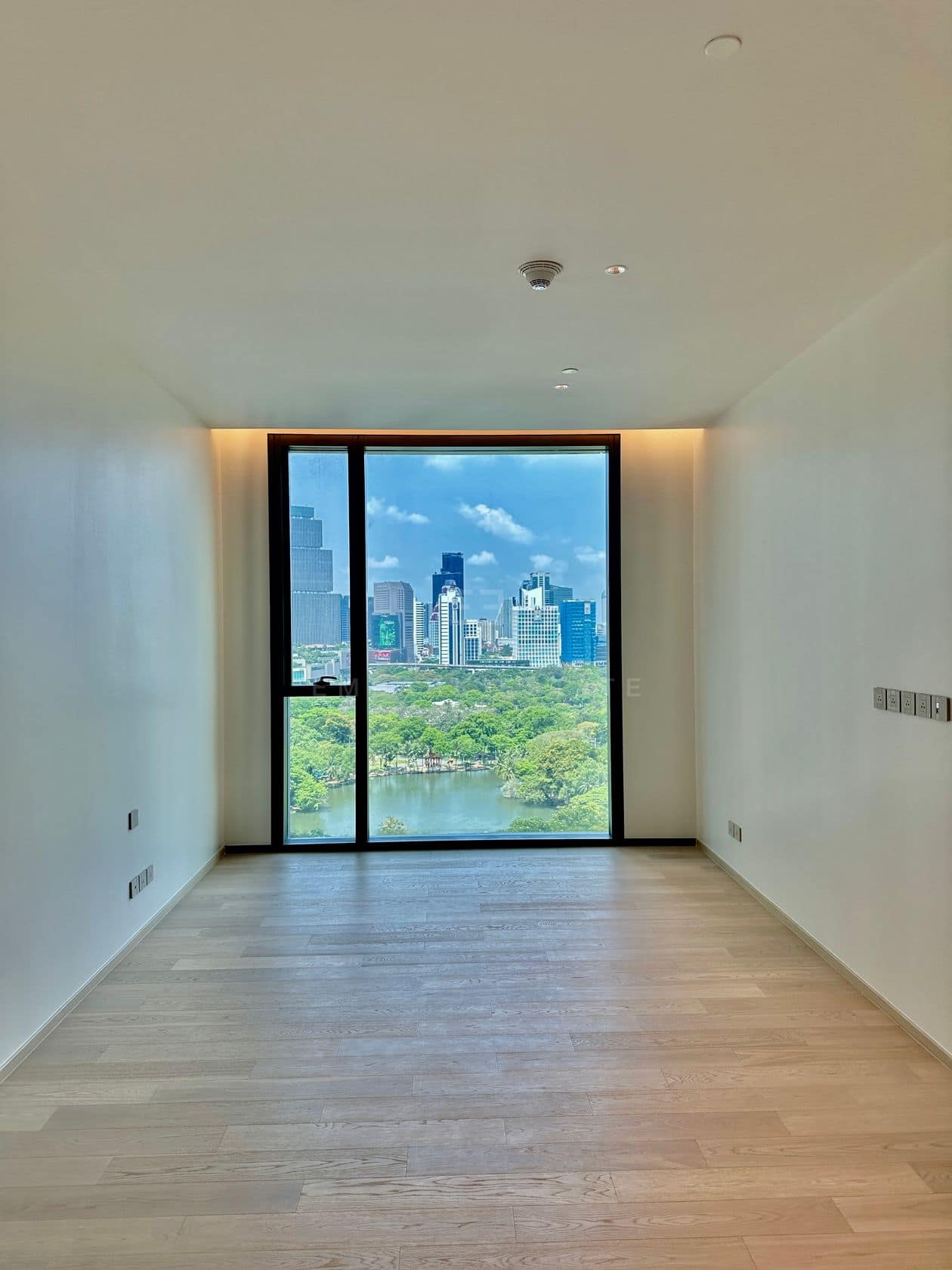 A bedroom of an unfurnished three-bedroom residence at EI8HTEEN SEVEN, One Bangkok, with a picture window over Lumphini Park
