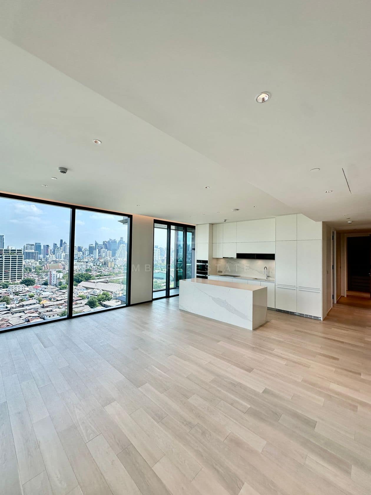 The open-plan living and kitchen of an unfurnished three-bedroom residence at EI8HTEEN SEVEN, One Bangkok, facing the central Bangkok skyline