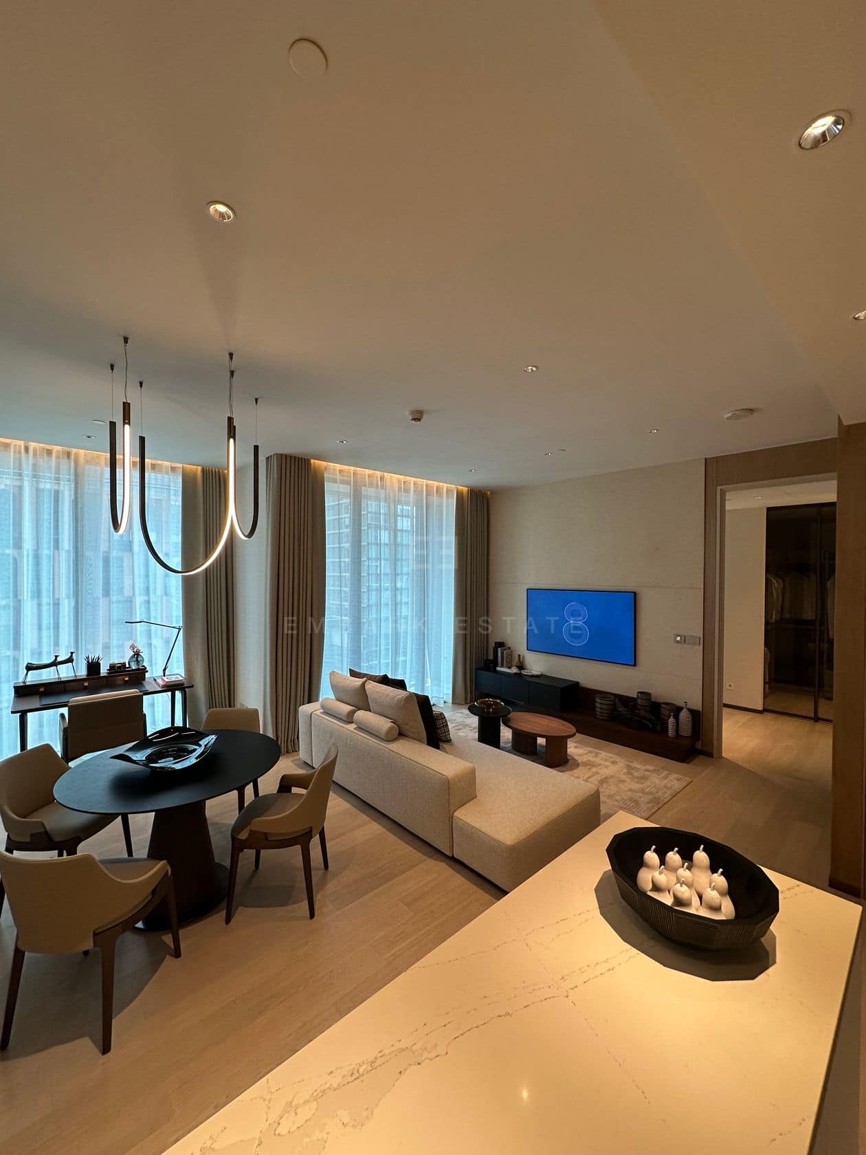 The living and dining area of a one-bedroom residence at EI8HTEEN SEVEN, One Bangkok, with a marble island, dining table and city view