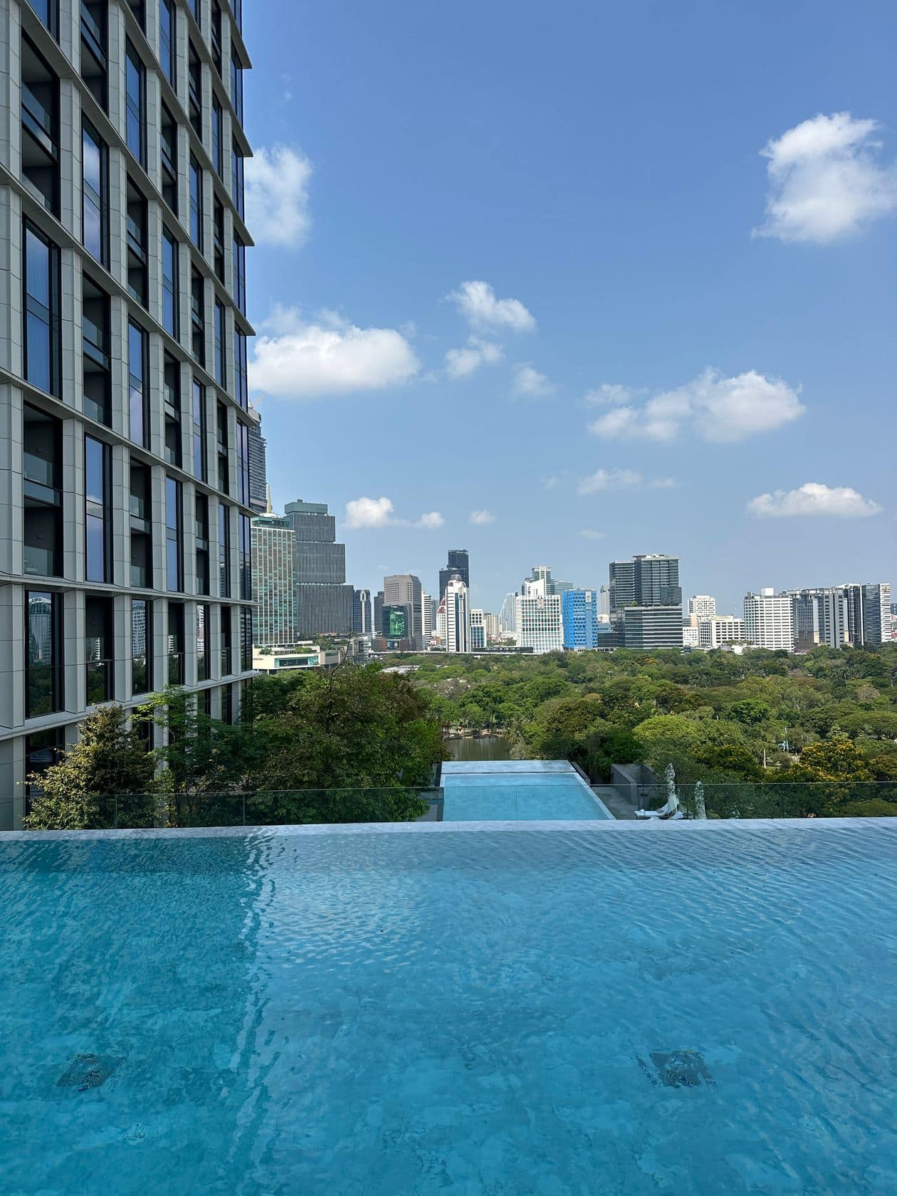 The landscaped roof garden terrace at EI8HTEEN SEVEN, One Bangkok, with a timber pergola and skyline view