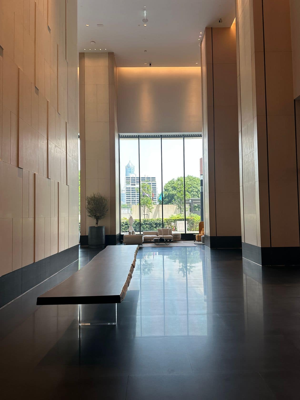 The double-height arrival lobby at EI8HTEEN SEVEN, One Bangkok, with floor-to-ceiling windows onto Lumphini Park