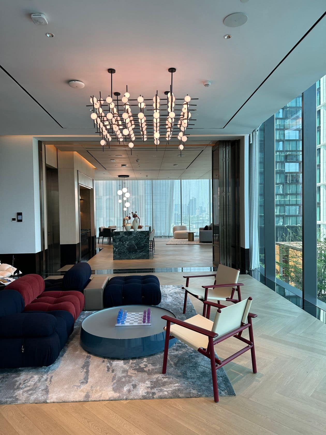 The reflecting pool and garden deck at EI8HTEEN SEVEN, One Bangkok, with a specimen tree and city view