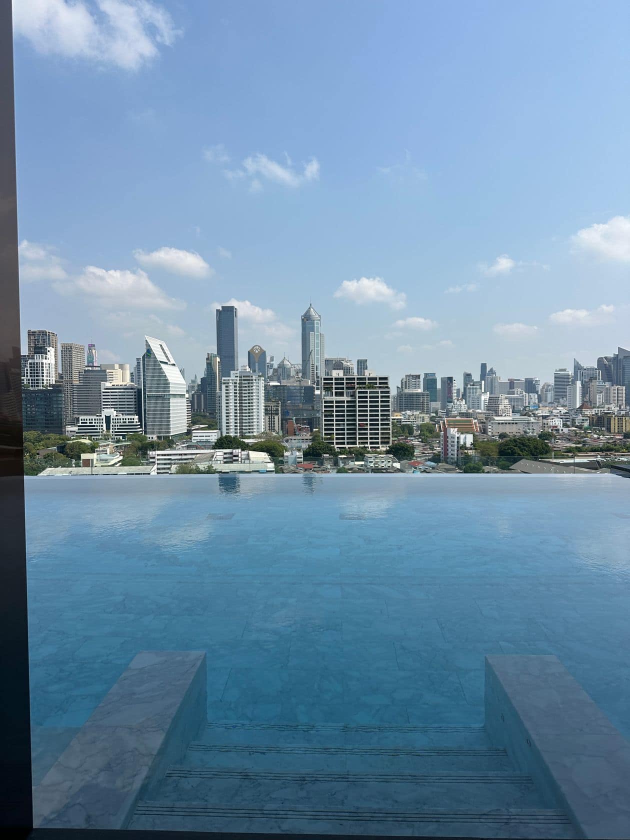 The infinity pool edge at EI8HTEEN SEVEN, One Bangkok, against the central Bangkok skyline