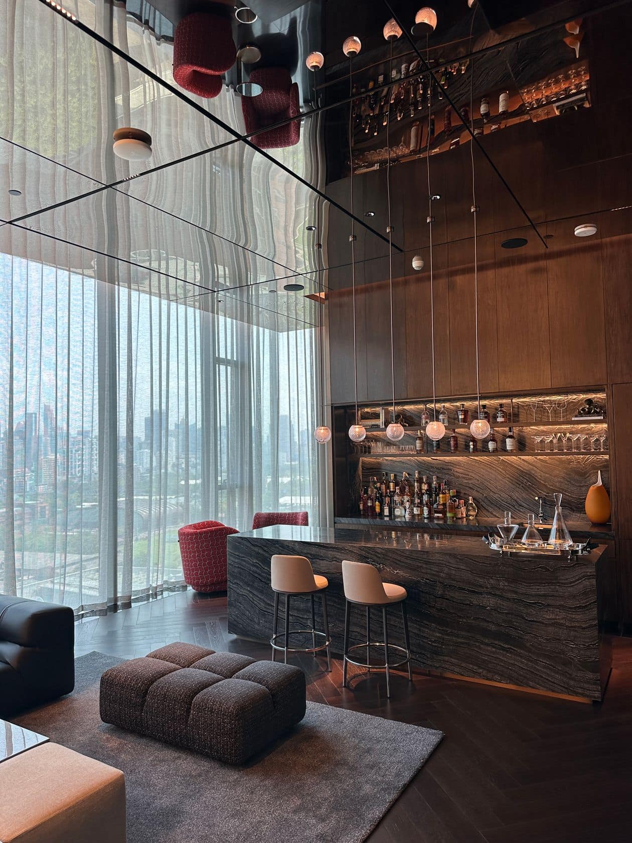 The residents' sky lounge at EI8HTEEN SEVEN, One Bangkok, with velvet armchairs and park-and-skyline windows