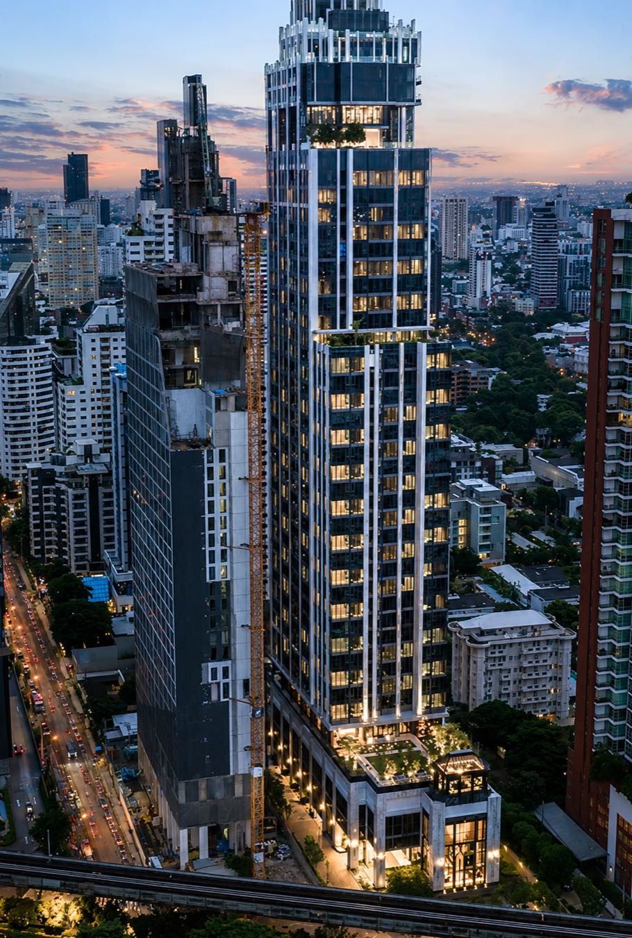 Hyde Heritage Thonglor: the tower lit at dusk above the Thonglor skyline and its rooftop sky garden in central Bangkok