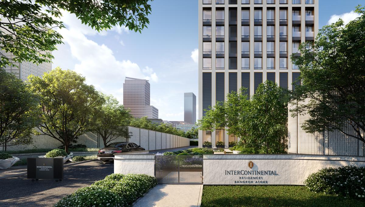 The arrival court at InterContinental Residences Bangkok Asoke: a stone signage wall carrying the InterContinental Residences Bangkok Asoke name beside a gated driveway, mature trees and clipped planting under the tower, an artist's impression