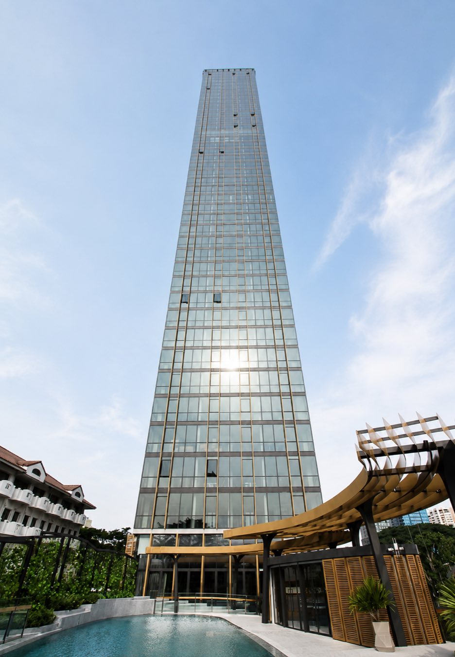The Monument Thong Lo: the gold-mullioned glass tower rising above the pool and arrival pavilion on Thonglor in central Bangkok, by Sansiri