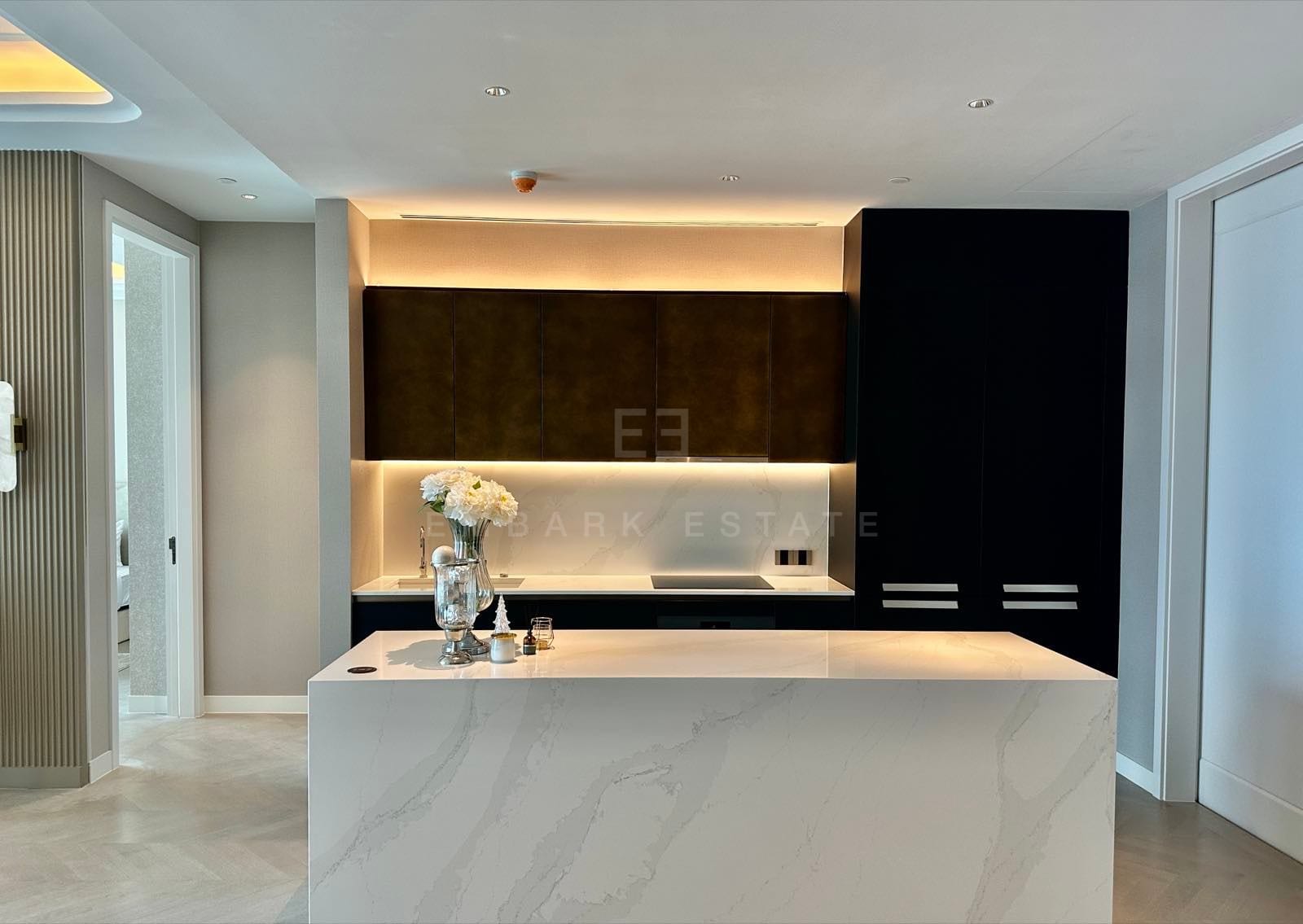 The kitchen of a two-bedroom residence at ONE89 Wireless, One Bangkok, with a marble island and dark timber joinery