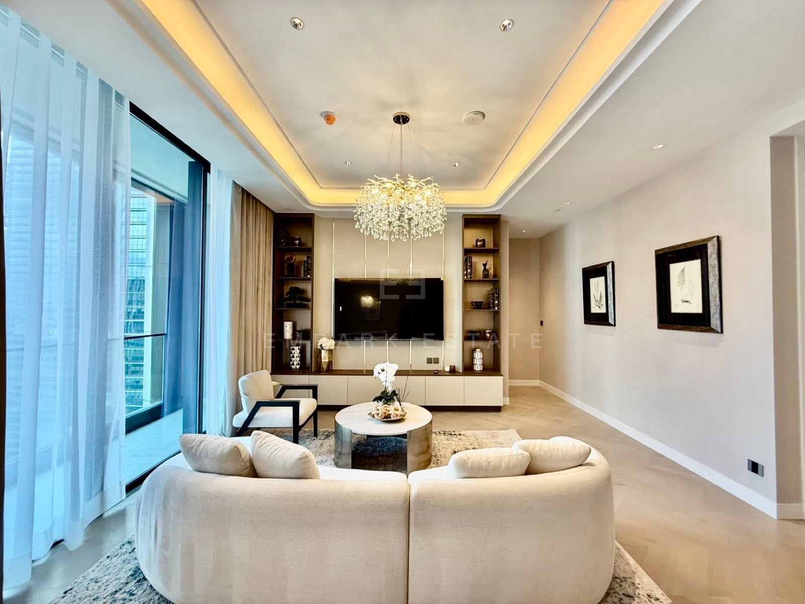 The living room of a two-bedroom residence at ONE89 Wireless, One Bangkok, with a curved sofa and a sculptural chandelier
