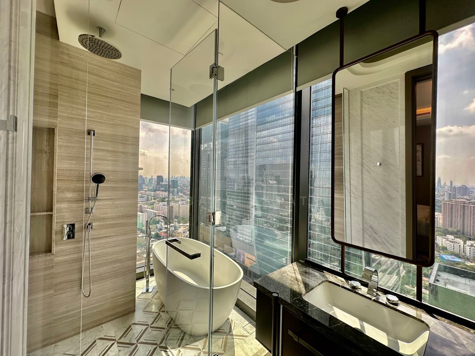 The marble principal bathroom of a two-bedroom residence at ONE89 Wireless, One Bangkok, with a walk-in shower, freestanding bath and skyline views