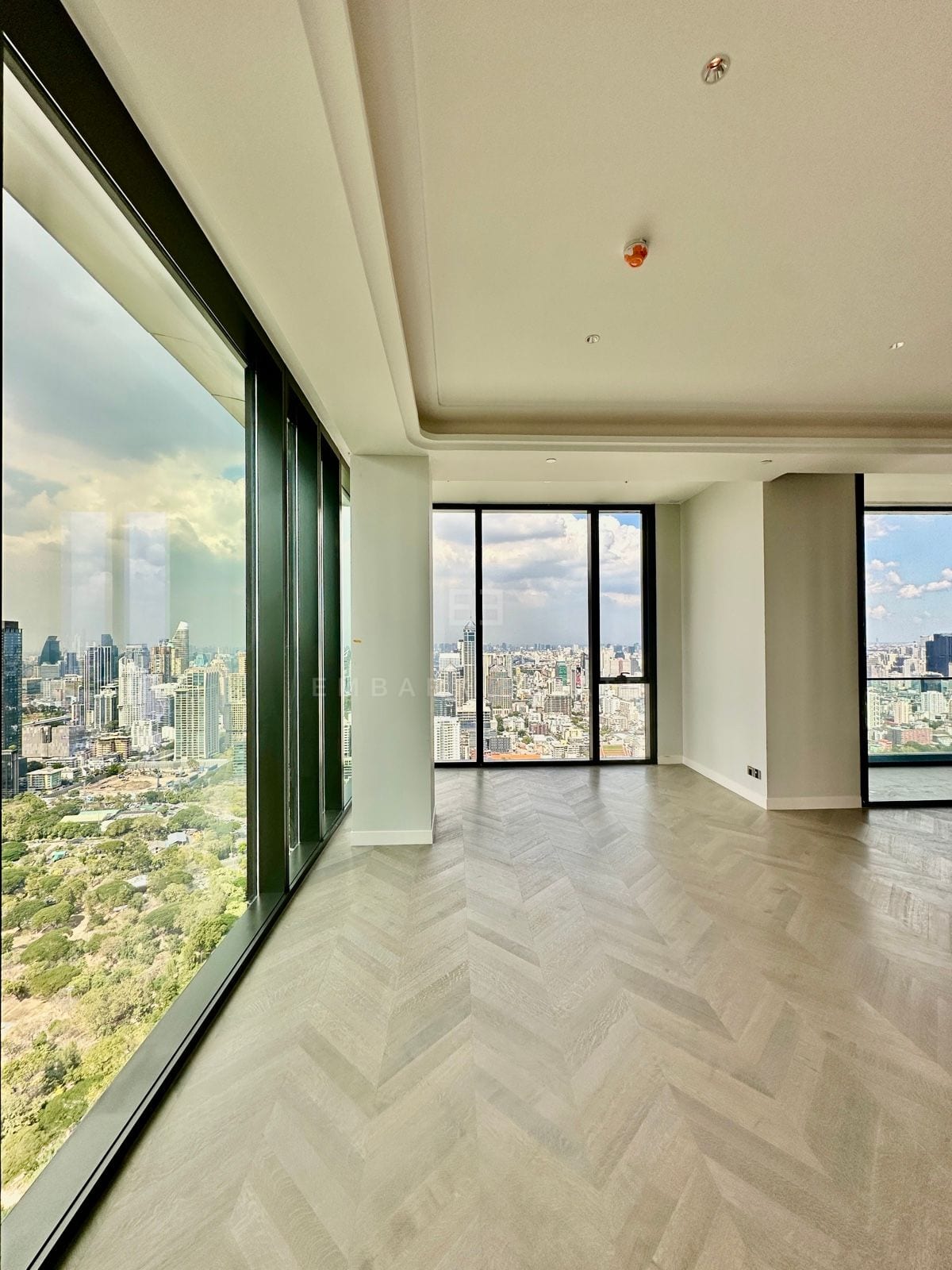 A corner living space of the 5-bedroom grand penthouse at ONE89 Wireless, One Bangkok, with full-height glazing over Lumphini Park and the skyline