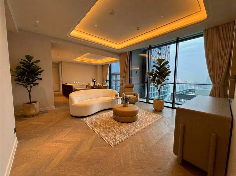 Living room of a two-bedroom residence at ONE89 Wireless, with a curved cream sofa, a round tan ottoman on a patterned rug and floor-to-ceiling windows facing a neighbouring tower.