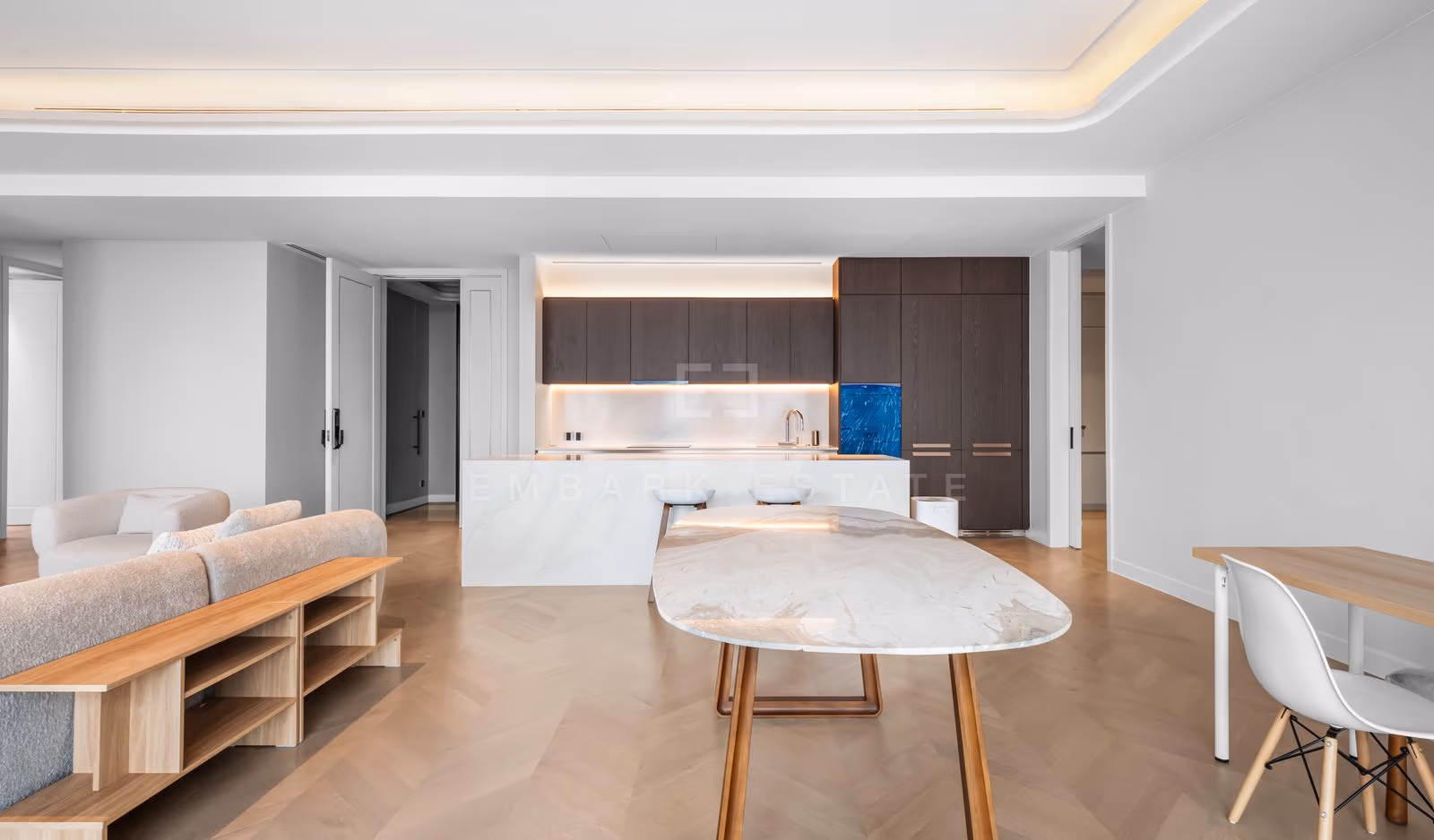 Dining area of a three-bedroom residence at ONE89 Wireless, Bangkok, with a marble dining table beside the island kitchen and dark timber cabinetry.
