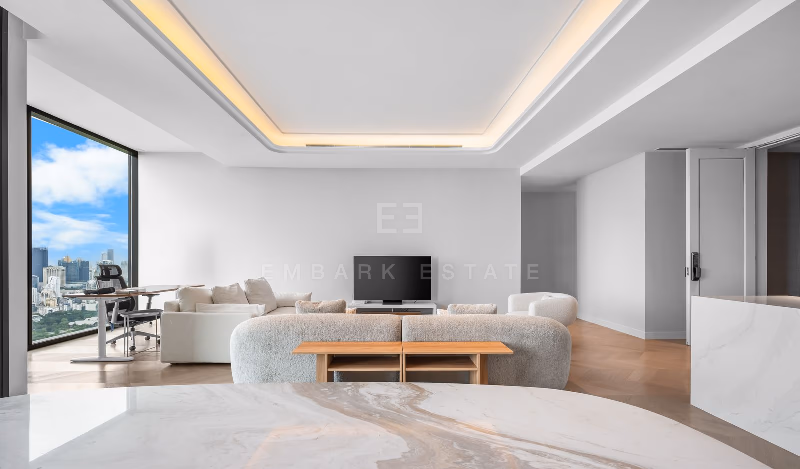 Living room of a three-bedroom residence at ONE89 Wireless, Bangkok, with a marble-topped coffee table, a television on a low console and full-height glazing to the balcony.