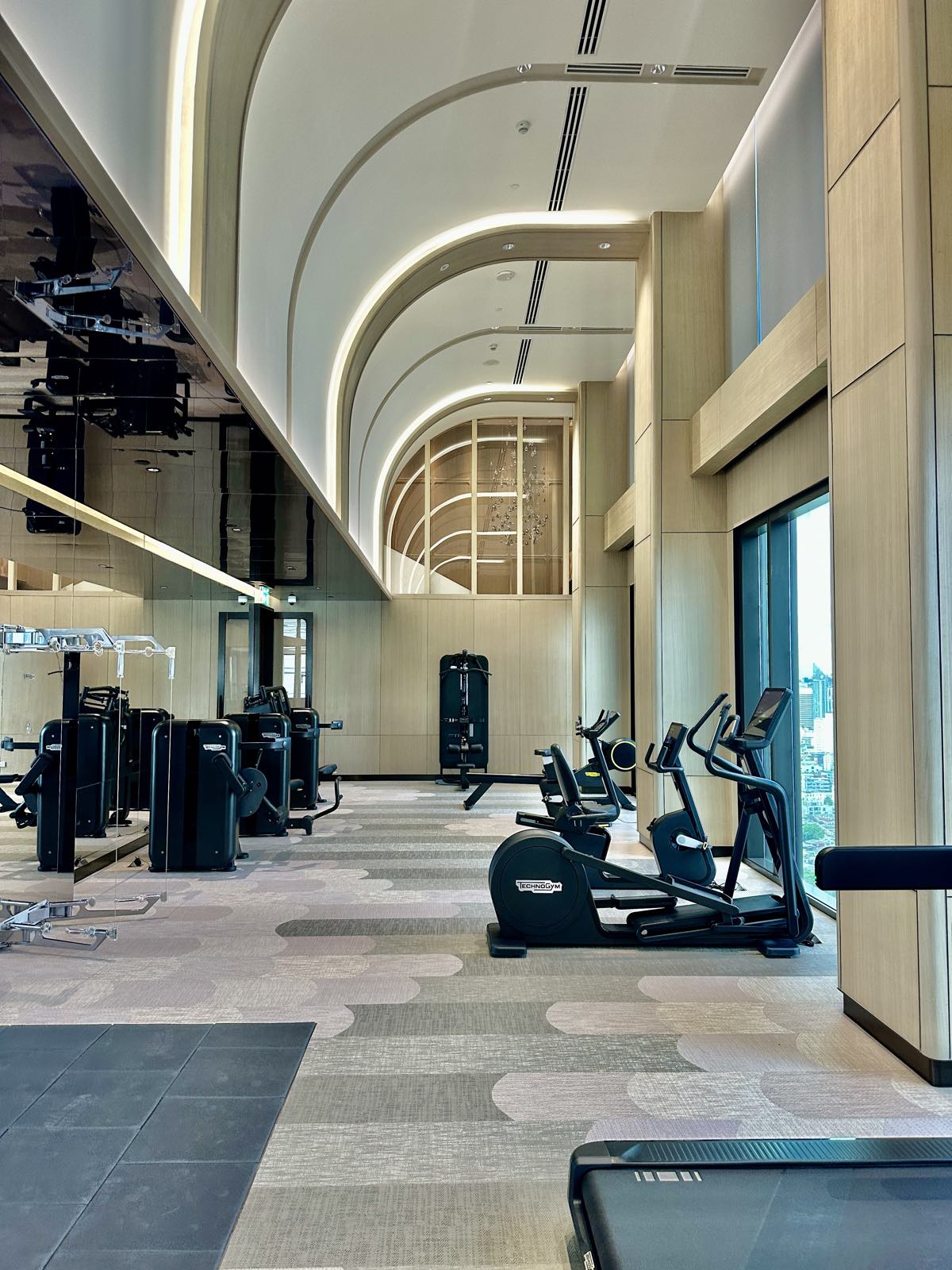 The fitness centre at ONE89 Wireless, One Bangkok, with Technogym equipment under a vaulted ceiling, a computer-generated render by One Bangkok