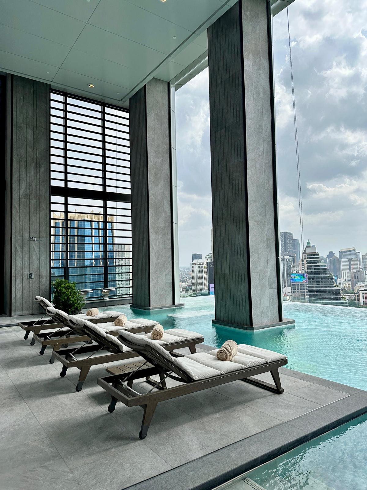The infinity-edge swimming pool with sun loungers at ONE89 Wireless, One Bangkok, overlooking the central Bangkok skyline