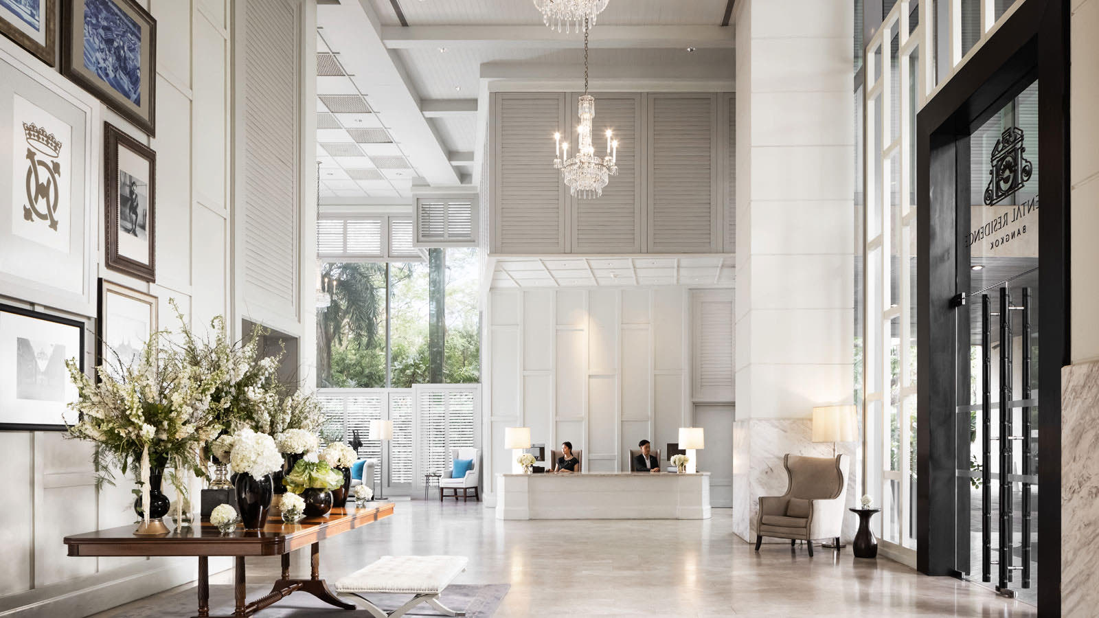 Oriental Residence Bangkok ล็อบบี้สีขาวสว่างพร้อมโคมระย้าและเคาน์เตอร์ต้อนรับ