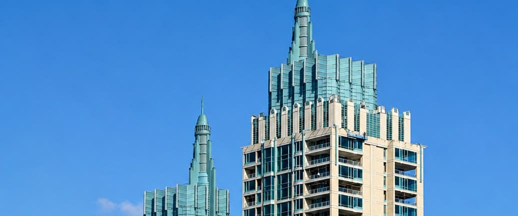 The pale-green spires and crowns of The Park Chidlom twin residential towers against a clear sky in central Bangkok