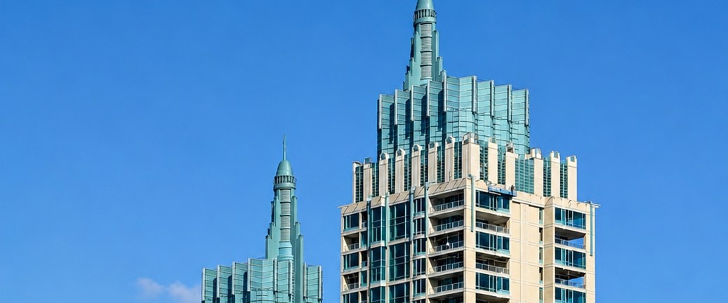 The pale-green spires and crowns of The Park Chidlom twin residential towers against a clear sky in central Bangkok