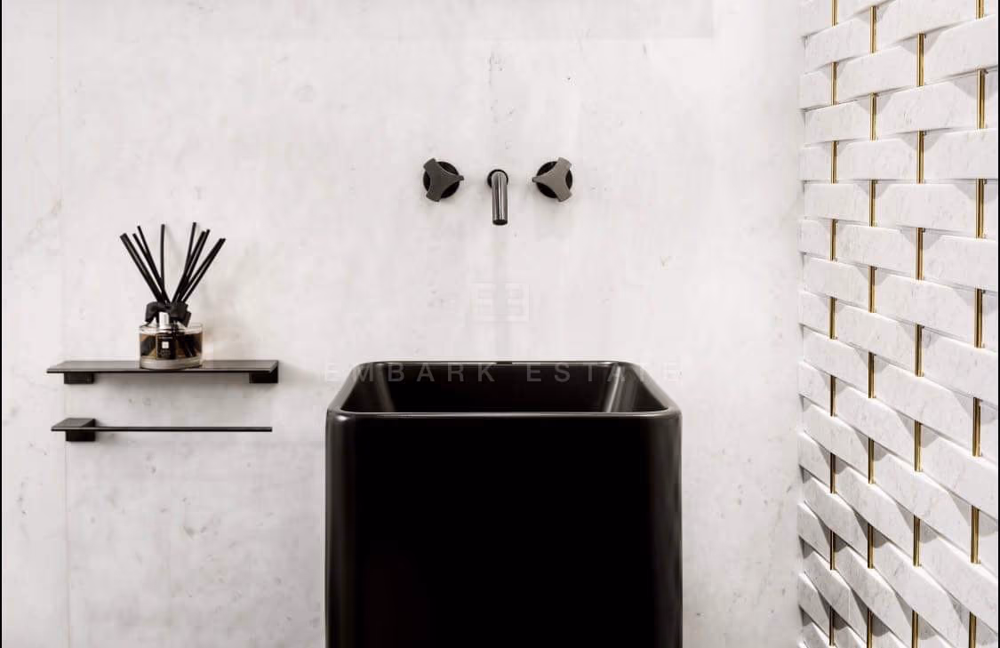 A washbasin at The Ritz-Carlton Residences Bangkok, a dark stone bowl on a shelf against a sculpted white tile wall, with wall-mounted taps