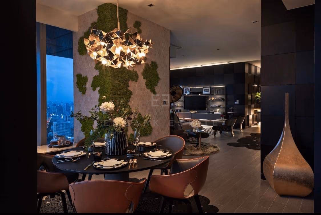 The dining room of a two-bedroom residence at The Ritz-Carlton Residences Bangkok, a round table under a sculptural pendant with planting and the city beyond