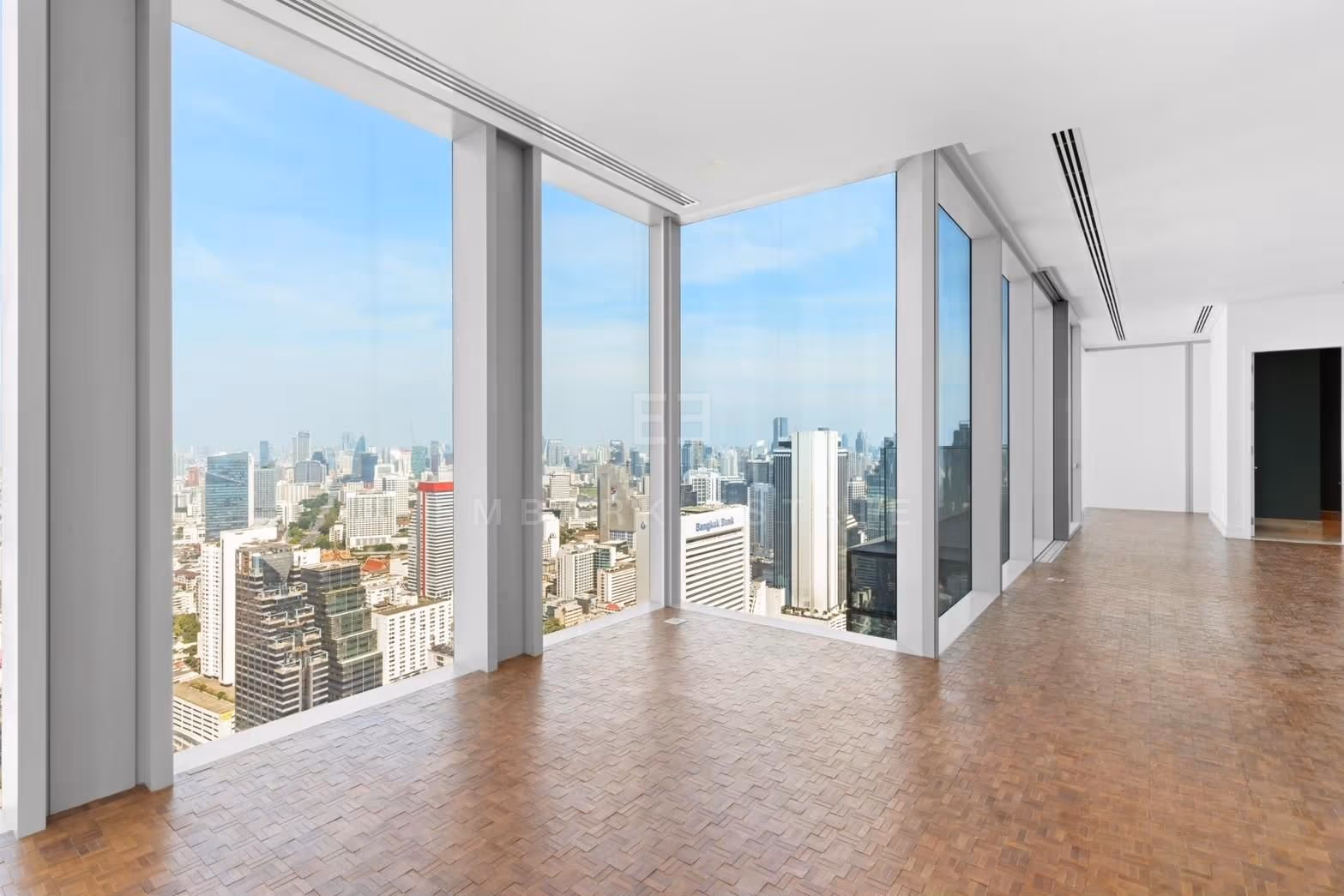 The reception room of a two-bedroom residence at The Ritz-Carlton Residences Bangkok, empty, with windows turning the corner over central Bangkok