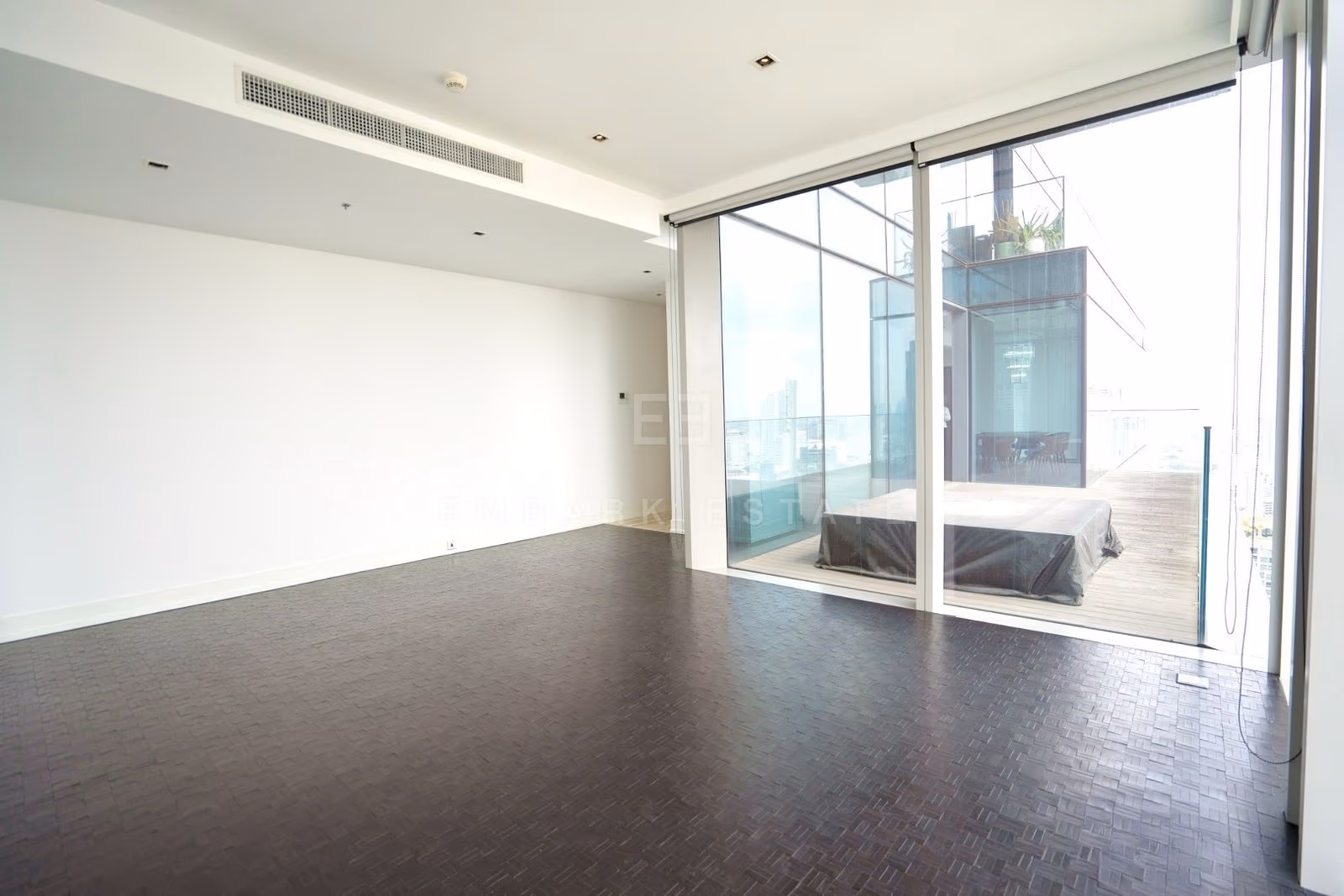 The living room of the 264 square metre residence on the 49th floor at The Ritz-Carlton Residences Bangkok, unfurnished, sliding glass onto the terrace and its glazed pavilion