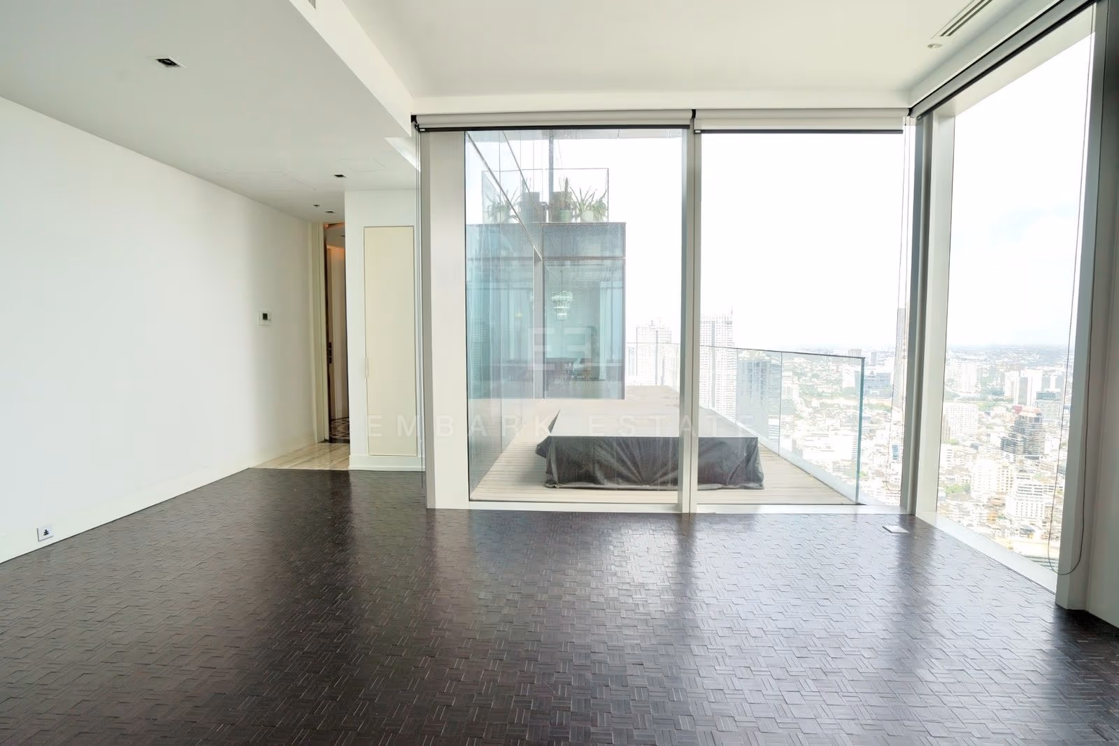 The living room on the 49th floor at The Ritz-Carlton Residences Bangkok, glazing turning the corner with the terrace along two sides