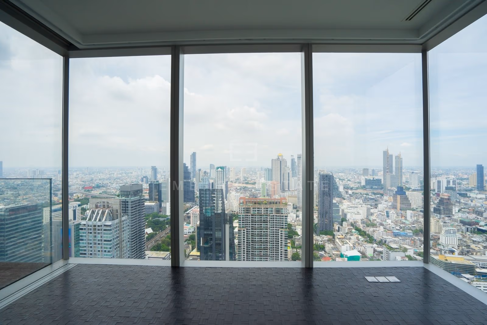 The living room on the 49th floor at The Ritz-Carlton Residences Bangkok, corner glazing under a dark coffered ceiling above central Bangkok