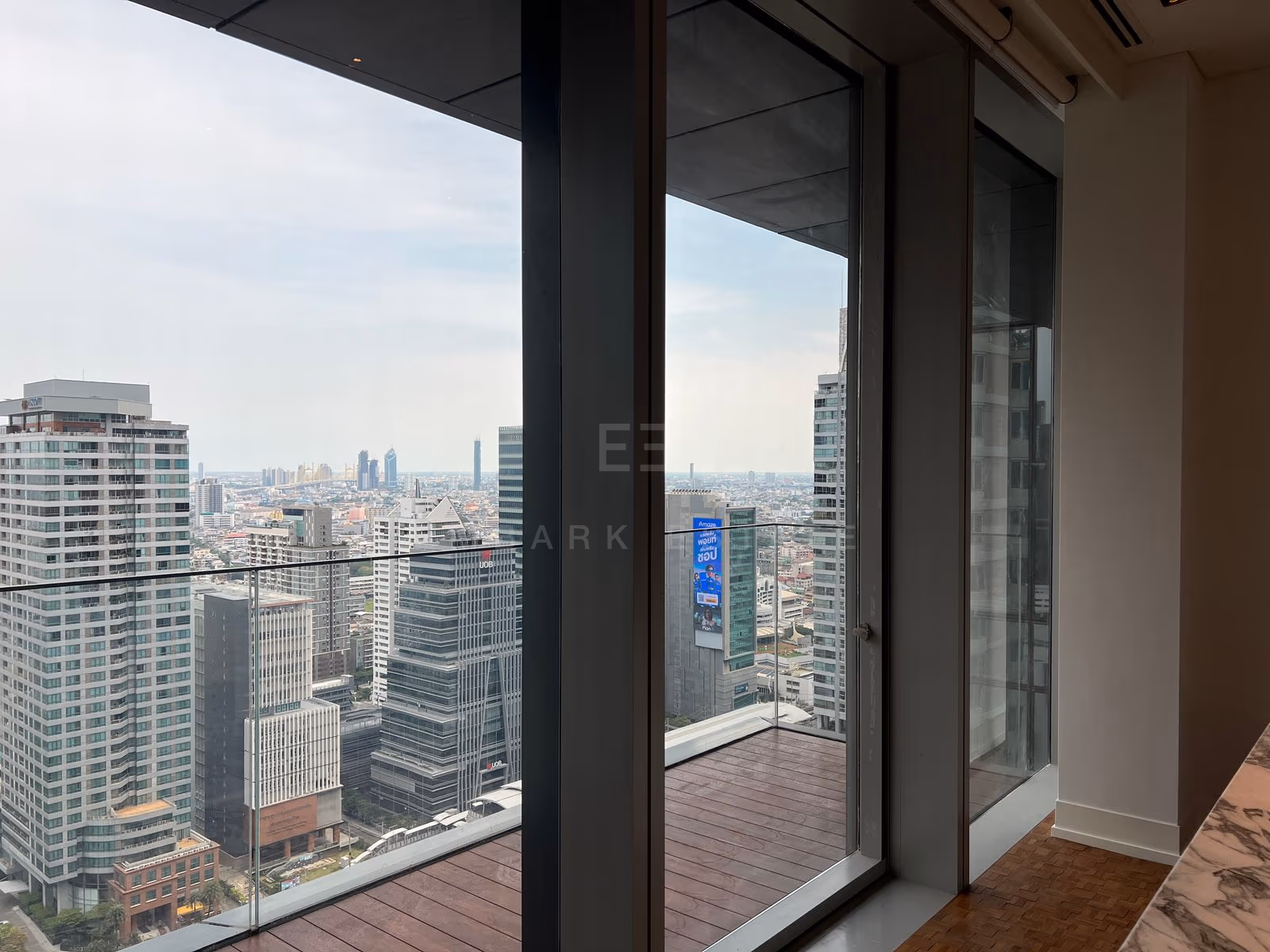 The living room on the 31st floor at The Ritz-Carlton Residences Bangkok, sliding glass onto the balcony and its terracotta decking