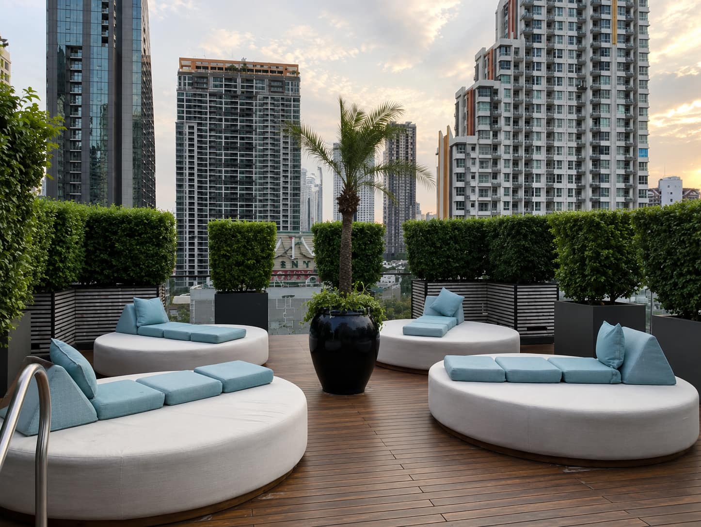 The Ritz-Carlton Residences Bangkok: circular daybeds on the landscaped rooftop lounge terrace with a Bangkok skyline view at sunset