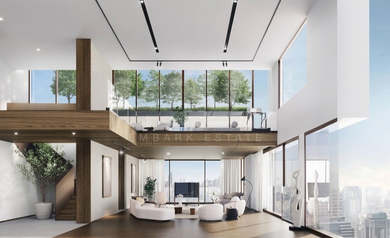 The double-height living room seen from the lower floor, with a timber staircase and an olive tree at left, a planted mezzanine terrace above, and corner glazing onto the Bangkok skyline, an interior visualisation of the 419 sq.m four-bedroom duplex penthouse at ROMM Convent, Convent Road, Bangkok