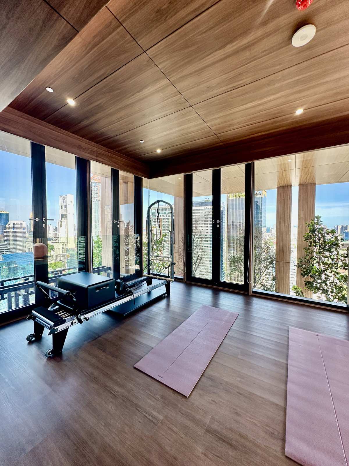 Pilates studio with a reformer and floor-to-ceiling glazing at ROMM Convent, Bangkok.