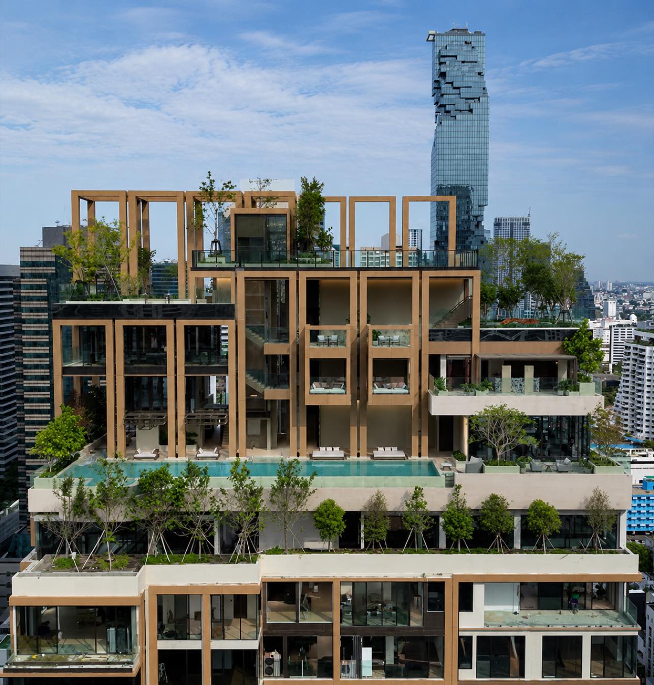 ROMM Convent: the planted terraces and rooftop pool of the building with the MahaNakhon tower on the Sathorn skyline behind, in central Bangkok
