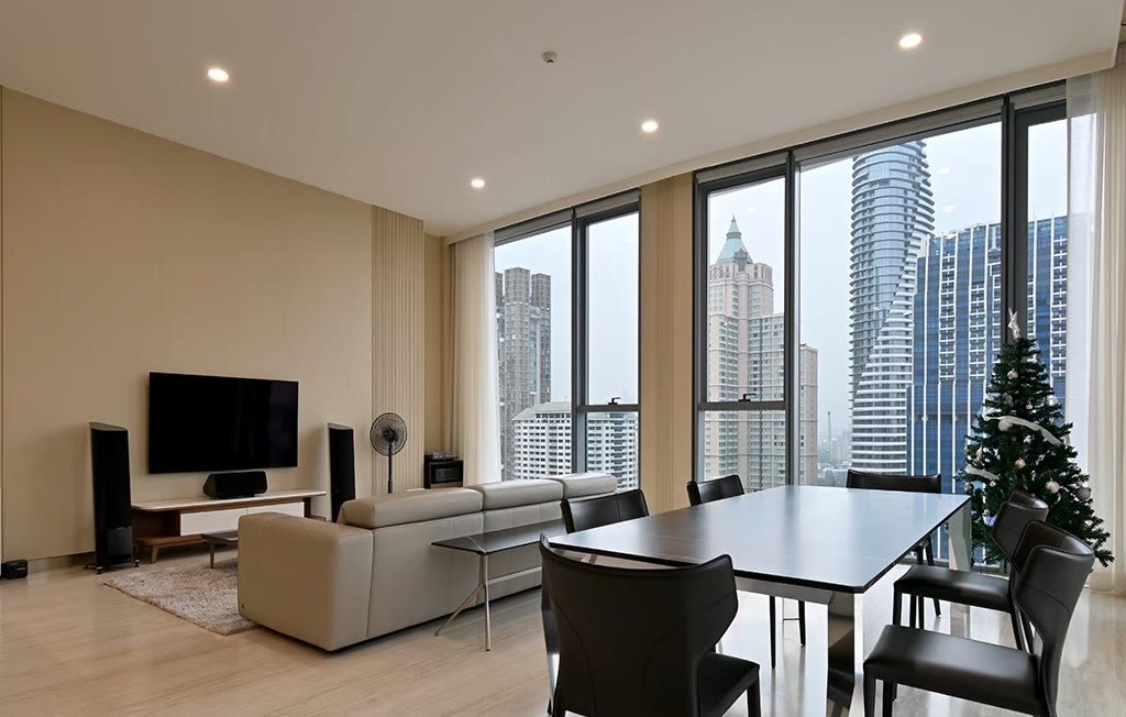 The furnished living and dining room of unit 2404 at Scope Langsuan, with floor-to-ceiling windows over the central Bangkok skyline