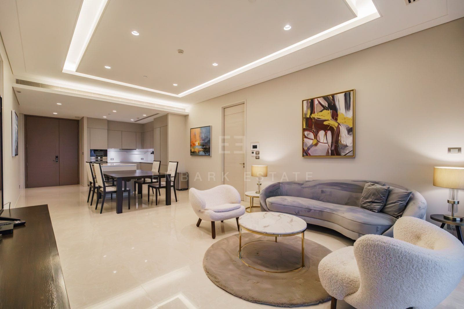 The living and dining area of the two-bedroom residence at the Residences at Sindhorn Kempinski, Bangkok, with a curved sofa and open kitchen
