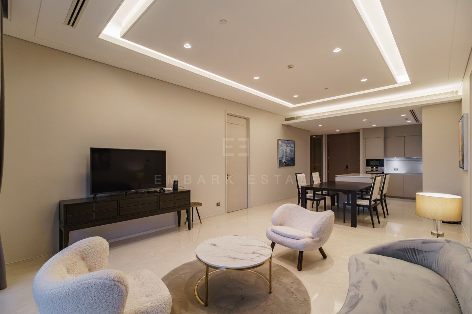 The living room of the two-bedroom residence at the Residences at Sindhorn Kempinski, Bangkok, with bouclé armchairs, a grey sofa and a wall-mounted television