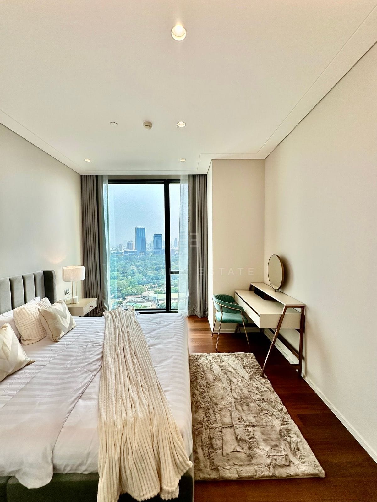 ห้องนอนห้องหนึ่งของยูนิตห้าห้องนอนที่ The Residences at Sindhorn Kempinski Hotel Bangkok พร้อมโต๊ะเครื่องแป้งและวิวสวนสีเขียว