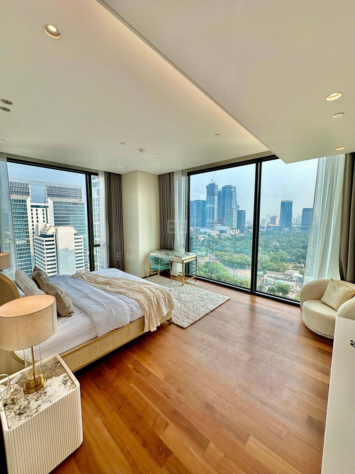 A corner bedroom in the 5-bedroom residence at the Residences at Sindhorn Kempinski, Bangkok, with windows over Lumphini Park and the skyline