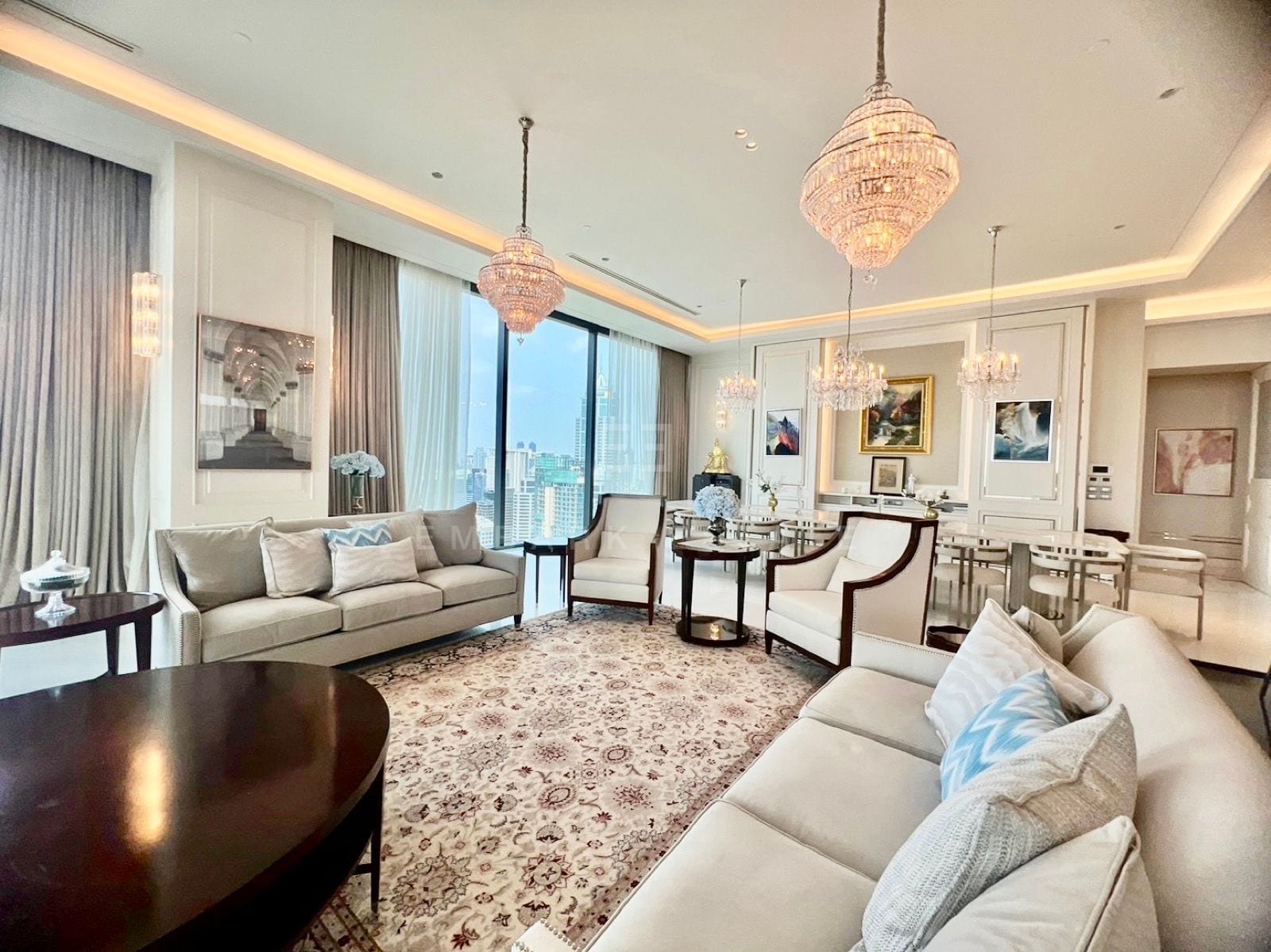 The living room of the Grand penthouse at the Residences at Sindhorn Kempinski, Bangkok, with crystal chandeliers, cream sofas and a patterned rug