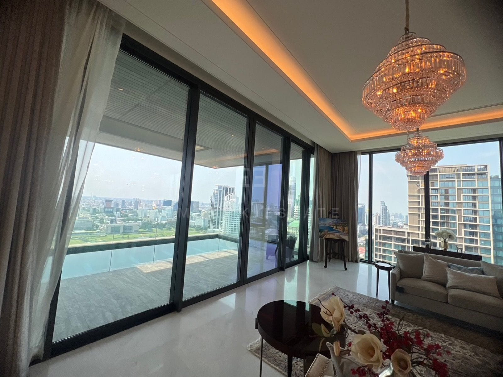 The living room of the Grand penthouse at the Residences at Sindhorn Kempinski, Bangkok, opening through glass doors to the private pool and the skyline
