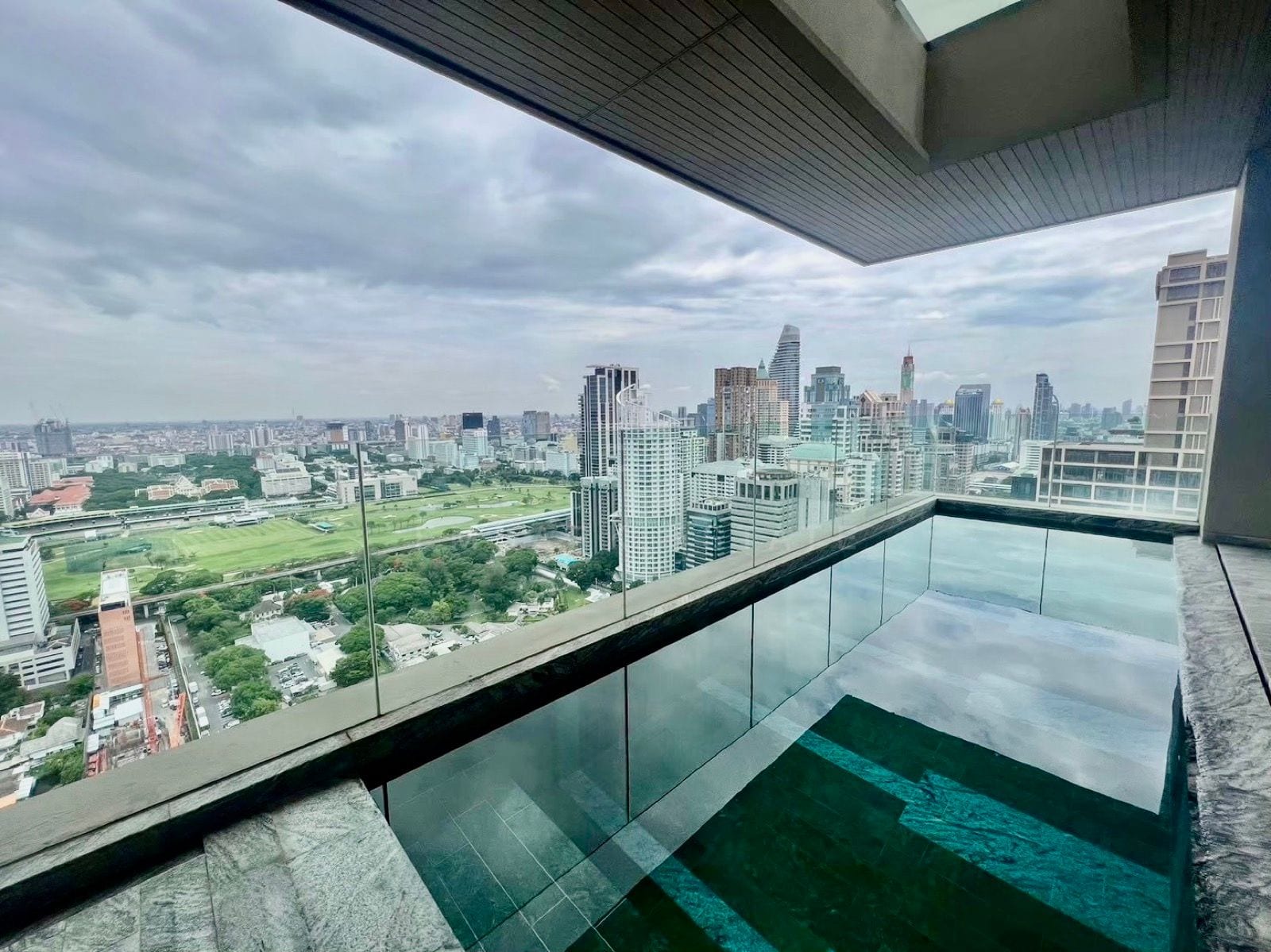 สระว่ายน้ำส่วนตัวและระเบียงของแกรนด์เพนต์เฮาส์ที่ The Residences at Sindhorn Kempinski Hotel Bangkok มองเห็นสนามหญ้าของราชกรีฑาสโมสรและเส้นขอบฟ้าเมือง