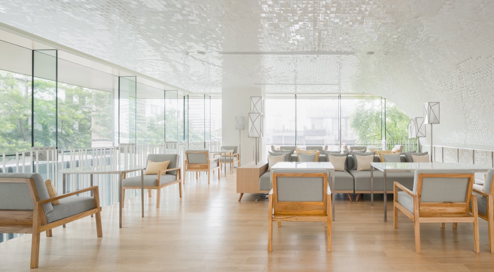 Bright residents’ lounge with garden views and a sculptural ceiling at Sindhorn Residence Langsuan