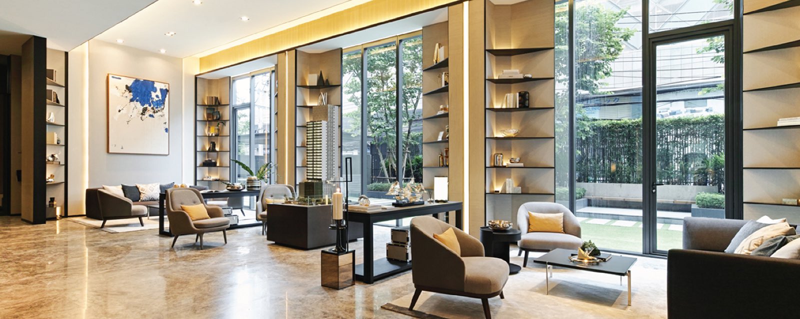 TELA Thonglor: Ground-floor lounge / library lounge with armchairs, bookshelves and floor-to-ceiling glass onto the garden