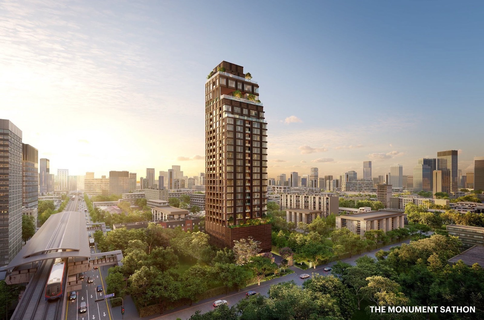 The Monument Sathon, an aerial render of the bronze-toned tower with planted terraces above tree canopy and low-rise blocks, an elevated rail station and train at left, and the Bangkok skyline behind