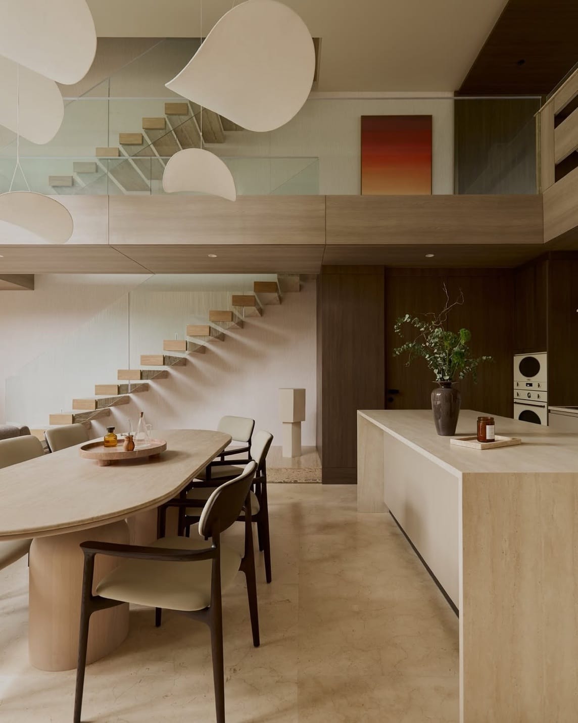 The stone kitchen island, dining table and floating timber staircase of the Type A show house at The Residenti Ekkamai, Bangkok