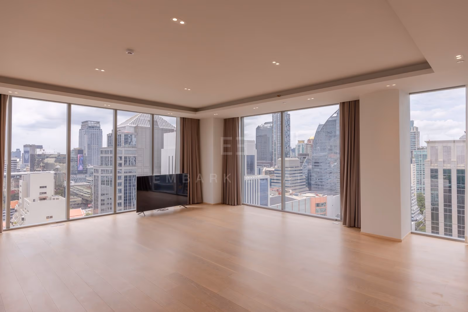 The living room of a three-bedroom residence at Tonson One Residence, the Ploenchit and Chidlom towers filling the window wall