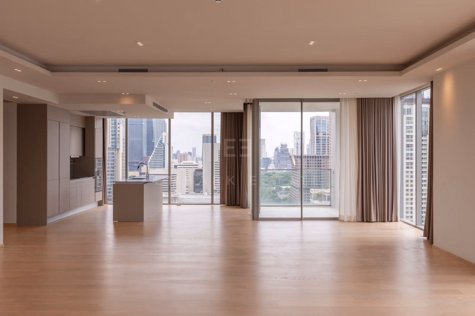 The open kitchen island at the far end of the living room in a three-bedroom residence at Tonson One Residence, with the balcony doors beside it